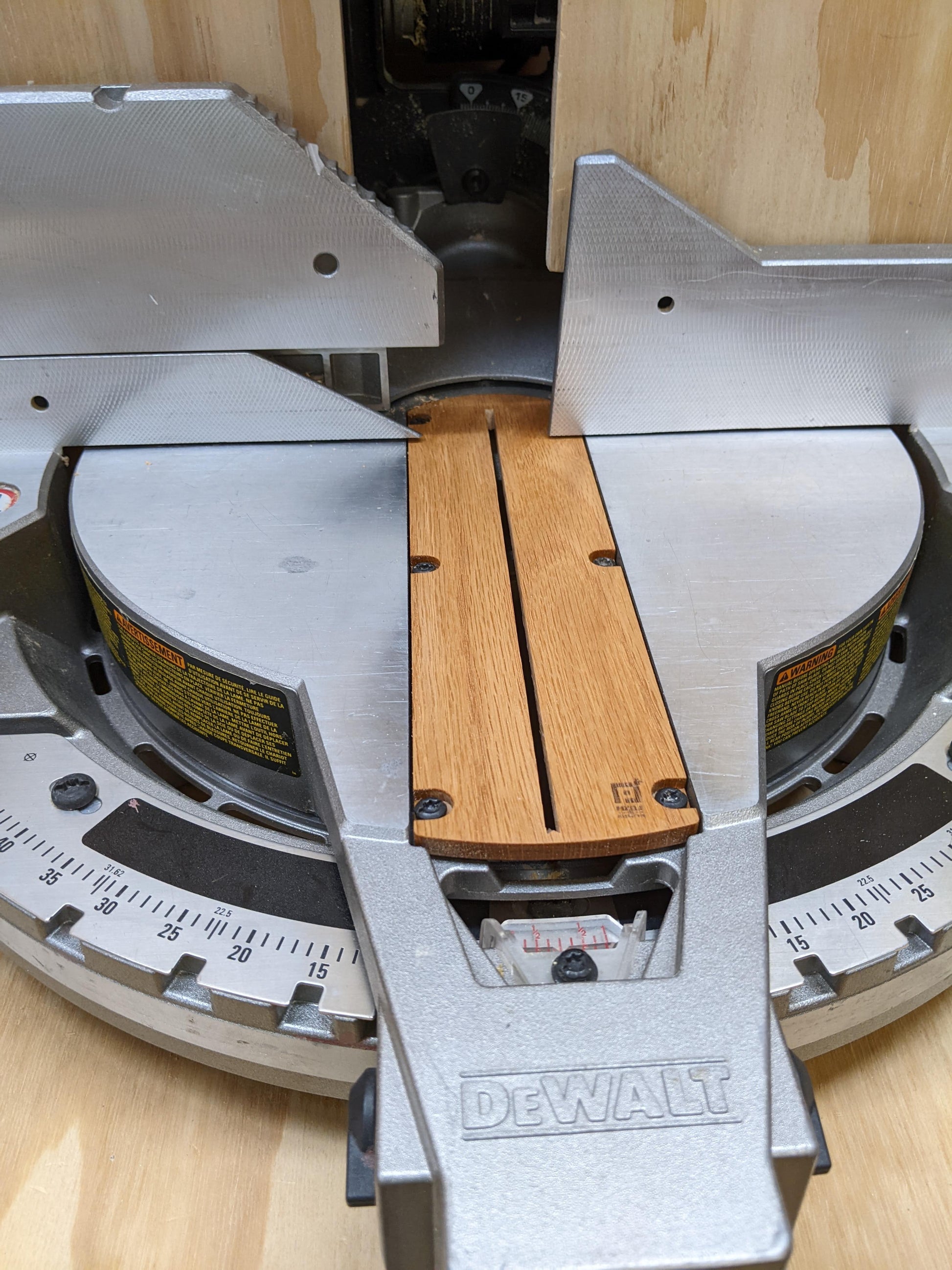 DEWALT miter saw with a piece of wood on the blade guard on a wooden surface